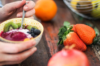 Person eating acai bowl with fruits